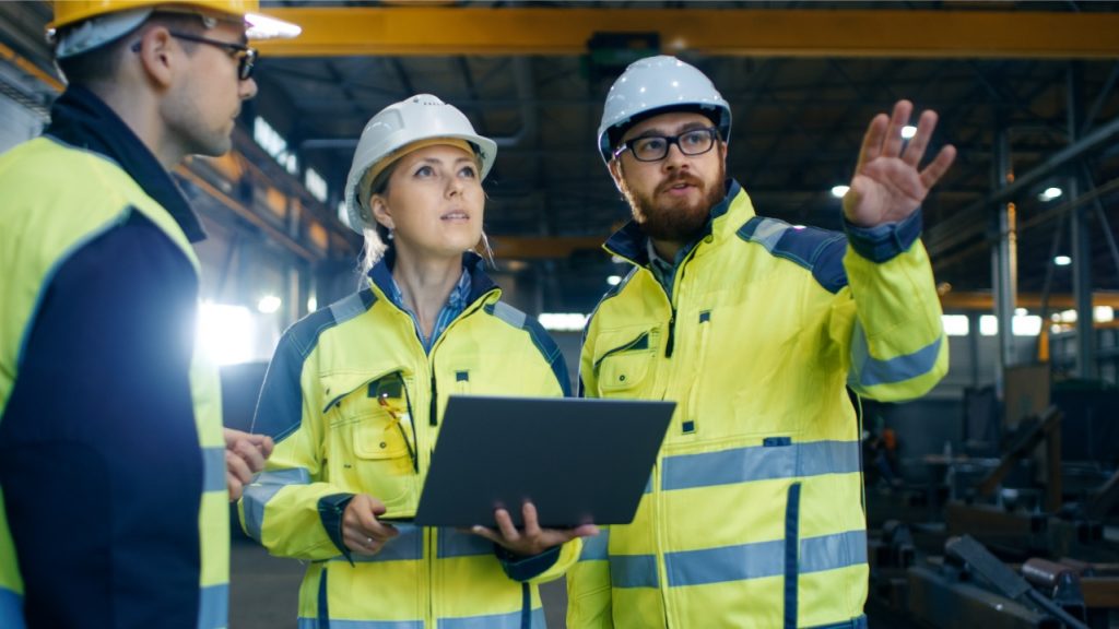 Three workers with hard hats looking at factory - Northmore Gordon